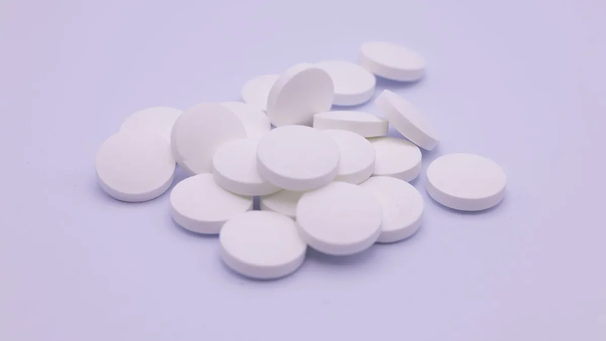 A detailed shot of white capsules in a black bowl, highlighting healthcare concerns. — Glass multi-dose injection vial on a clinical counter with a pharmacy label showing a lot number