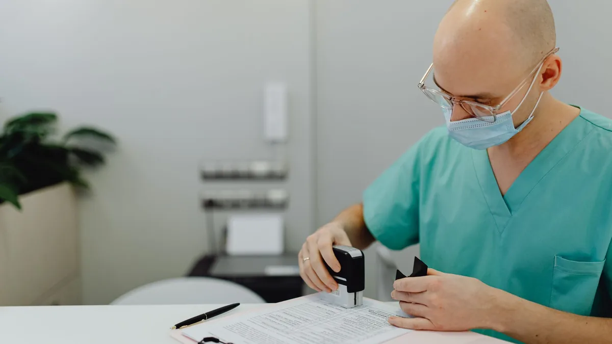 Healthcare worker in scrubs reviewing patient files with a stamp and clipboard. — Illustration accompanying a report on the once-monthly semaglutide depot entering a Phase 1/2a trial