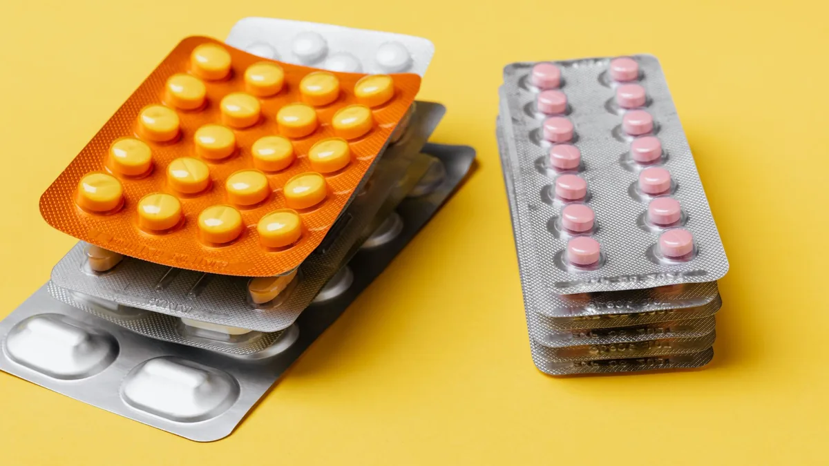 Heaps of various medication pills of different color and shape in blister packs placed on bright yellow background — Illustration accompanying coverage of the new Phase 3 oral semaglutide weight loss trial registration