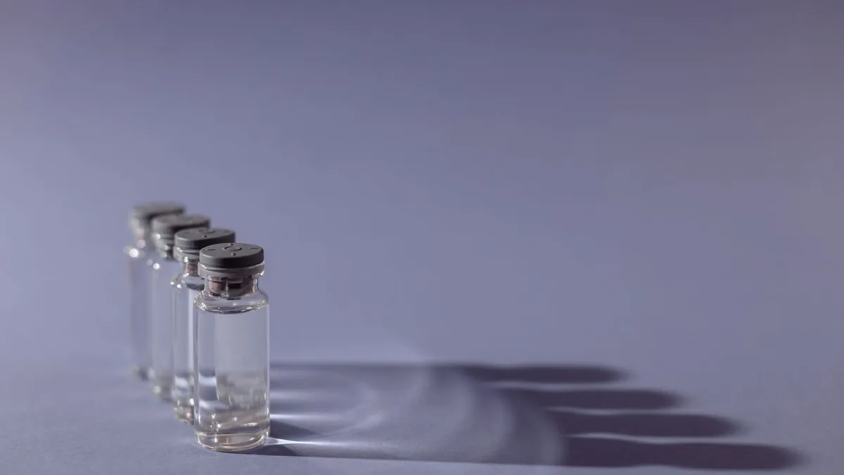 Close-up of lined up vaccine vials casting shadows, symbolizing medical advancements and health. — Lyophilised peptide vial with an unbranded label beside a laboratory analysis printout