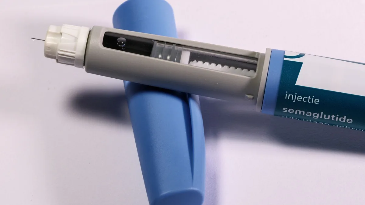 Detailed view of a semaglutide injection pen, commonly used for diabetes treatment, on a plain background. — Weekly injection pen beside a paper calendar used to record daily alcohol consumption