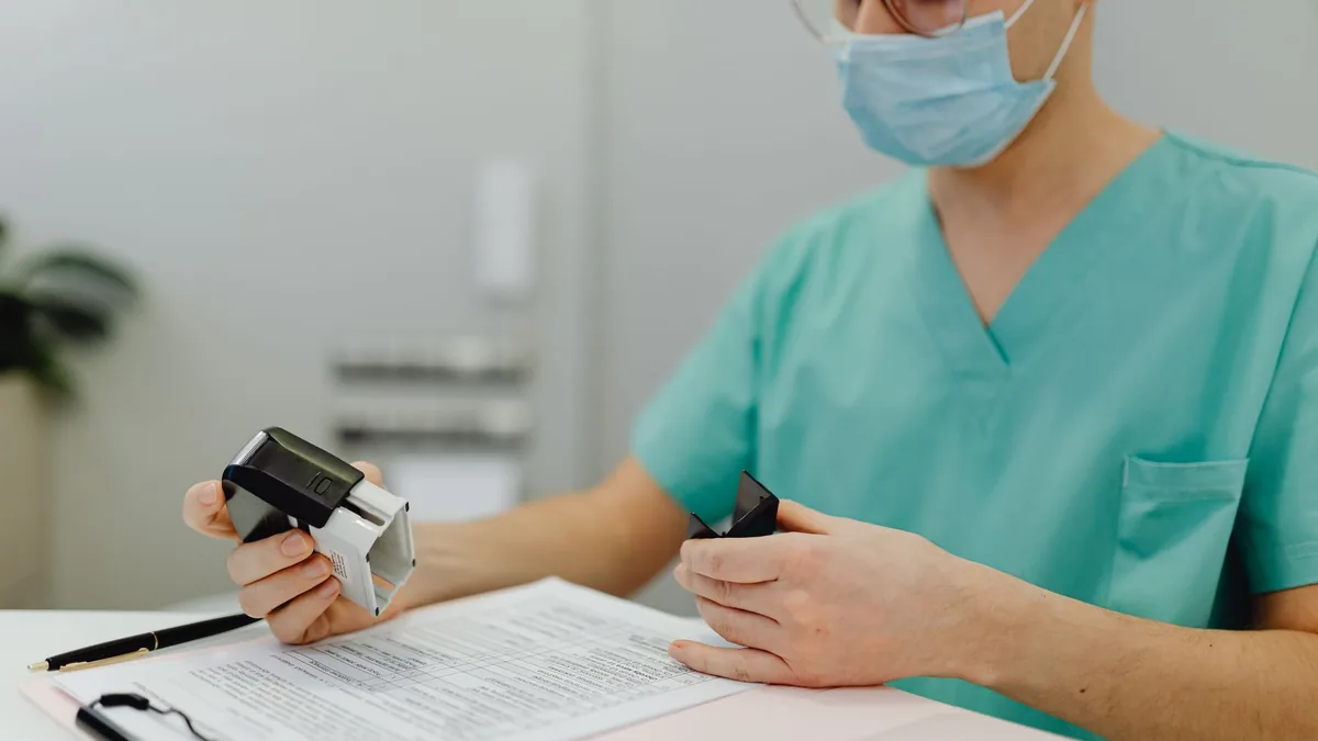 Healthcare worker in scrubs reviewing patient files with a stamp and clipboard. — Article illustration for a report on tirzepatide combination therapy trials registered in August 2026